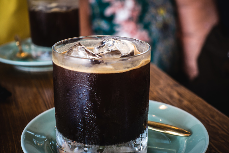 Carajillo. Bebida a base café con licor 43 servido sobre un vaso de vidrio con hielos, encima de un plato color verde